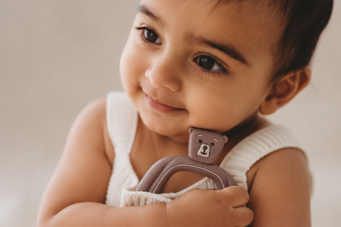 A baby holding a Bear Buddy teether